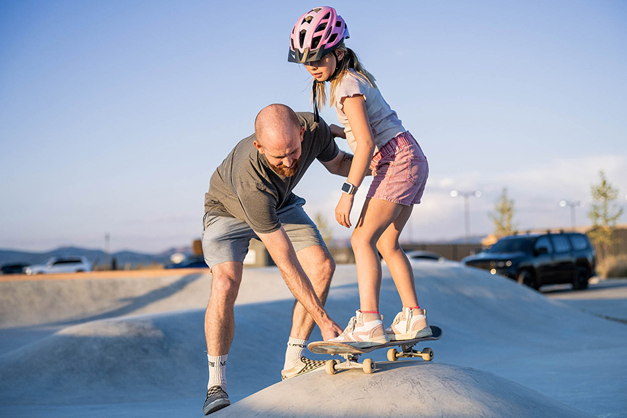 A father teaching his daughter how to skateboard at the Firefly skatepark in Eagle Mountain, Utah